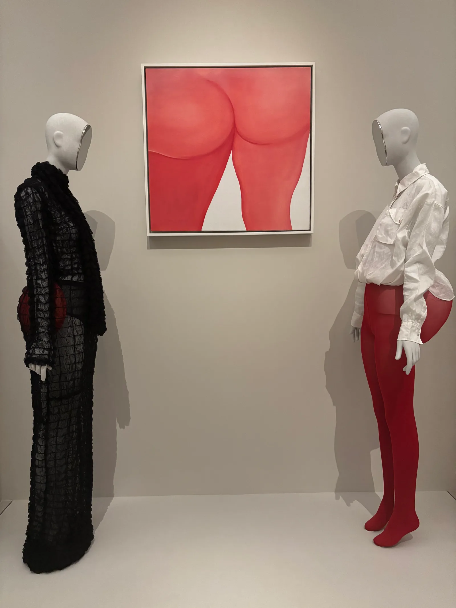 Two fashion mannequins with exaggerated padded hips and rear ends flank a bright red painting of buttocks at the Met’s “Costume Art” exhibition.